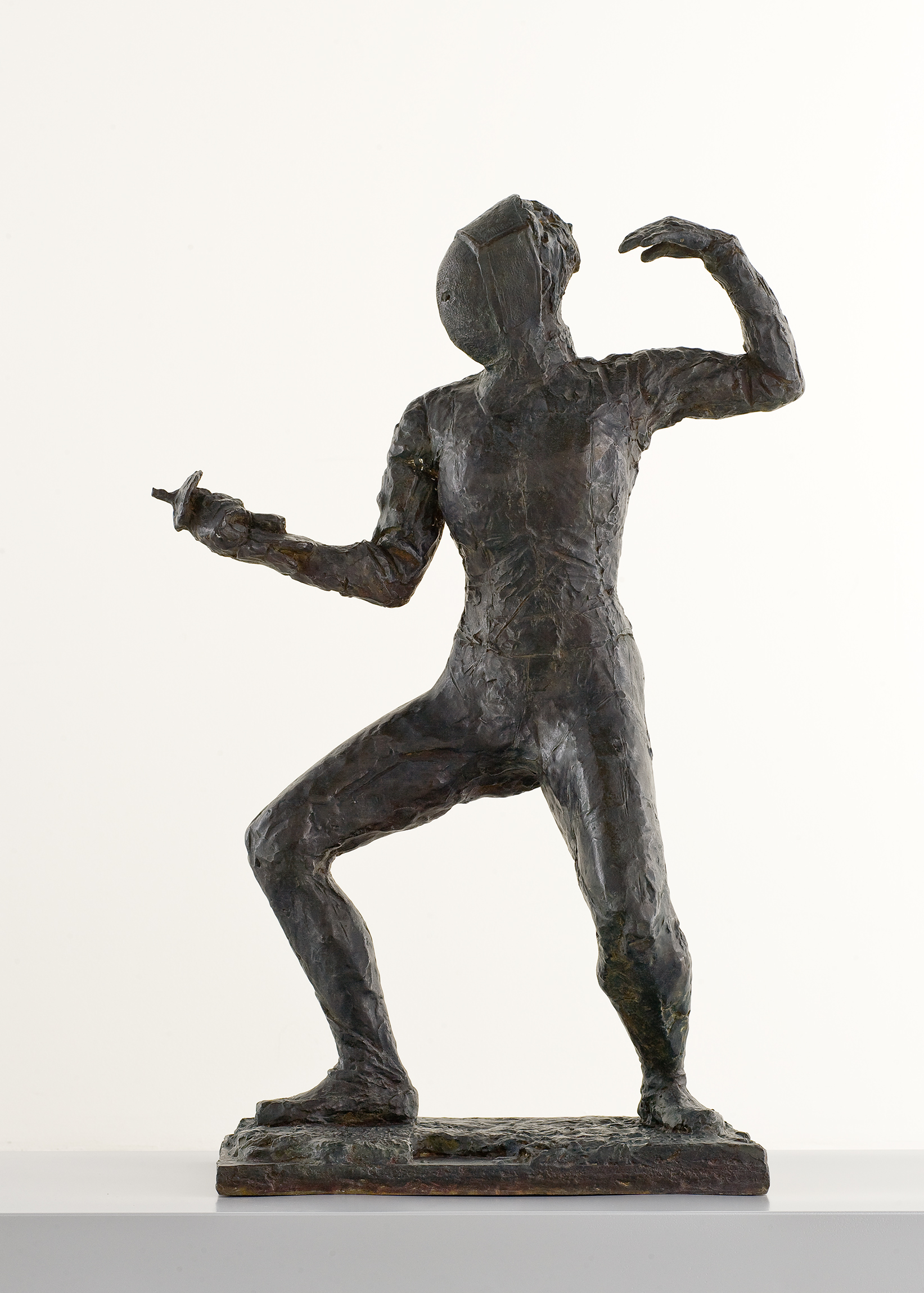 Cette image montre une sculpture en bronze représentant une figure humaine en posture dynamique. La sculpture illustre un sportif, vraisemblablement un escrimeur, vêtu d'un masque et tenant une épée. L'artiste a capturé le mouvement et l'énergie du personnage, qui semble prêt à se défendre ou à attaquer. Les détails du corps et les expressions sont stylisés, mettant l'accent sur la forme et la fluidité du geste. Le socle sur lequel la sculpture repose est simple, permettant à l'œuvre de se démarquer.