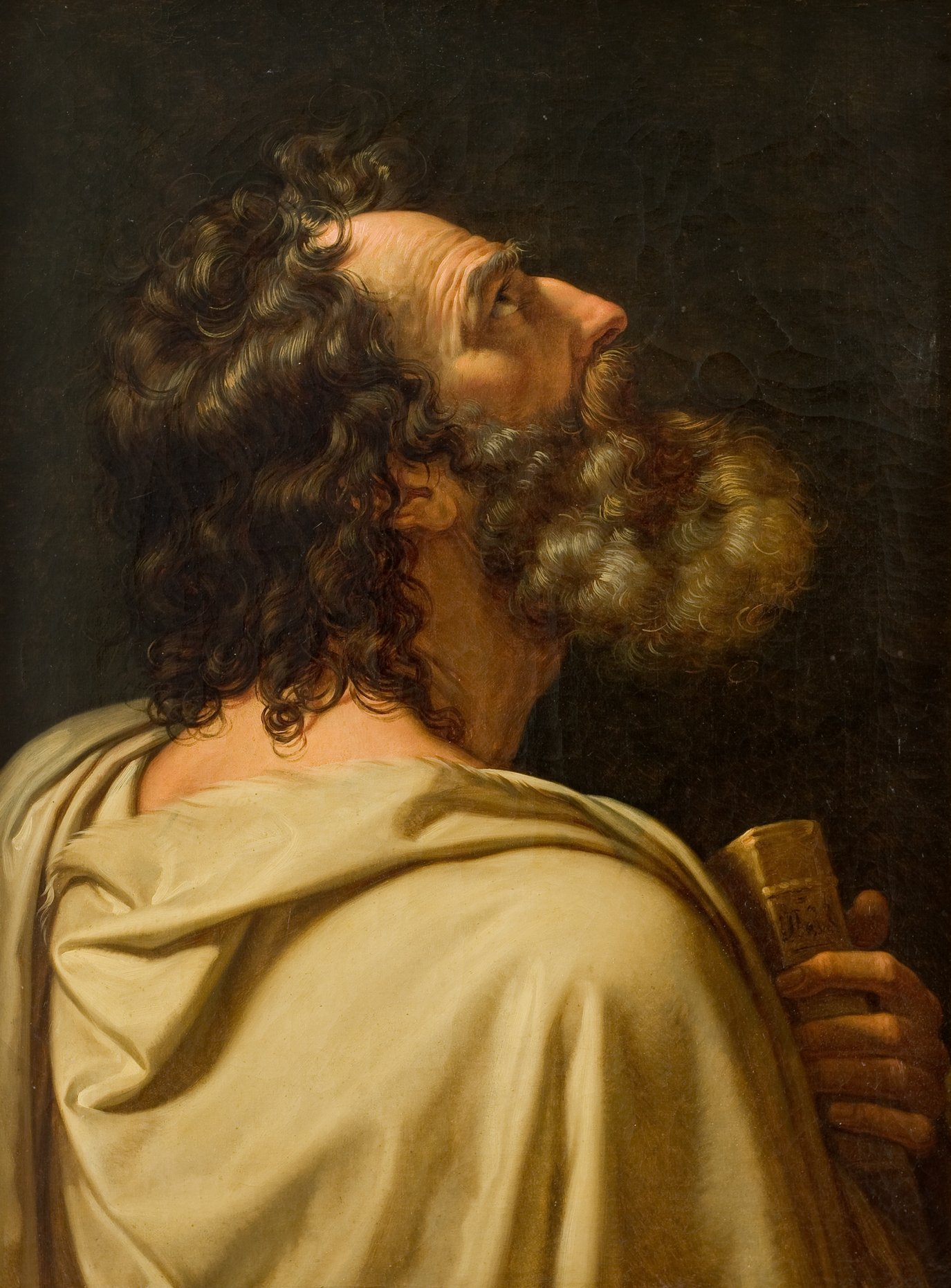 L'image représente un homme avec une expression contemplative, regardant vers le haut. Il a des cheveux bouclés et une barbe fournie. Son regard semble intense, suggérant de la profondeur ou de la réflexion. Il porte une draperie beige, et l'arrière-plan est sombre, ce qui met en valeur son visage et sa posture. L'éclairage accentue les détails de ses traits et crée un contraste avec l'obscurité environnante. L'ensemble de l'œuvre dégage une atmosphère solennelle et introspective.