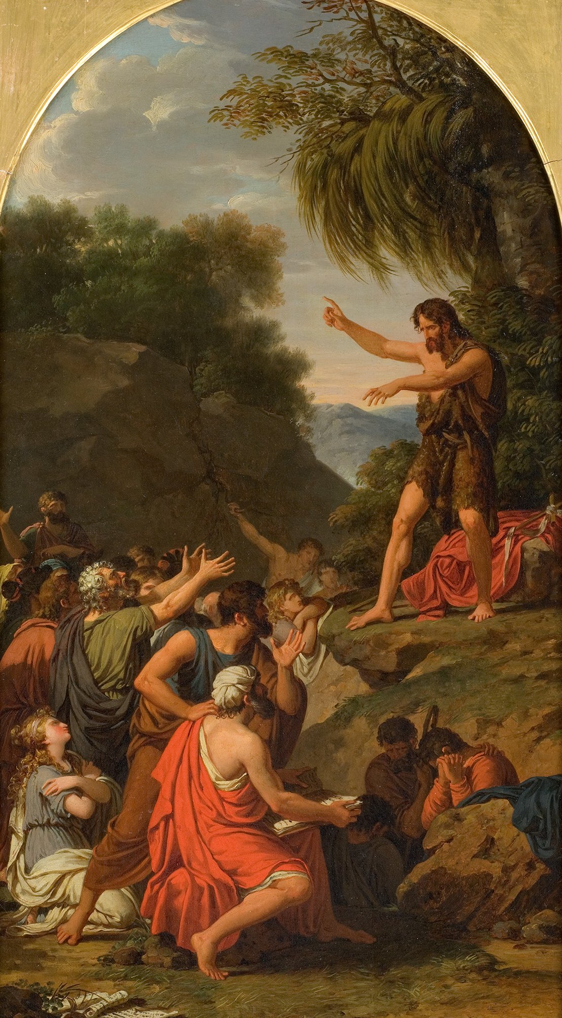 Cette image représente une scène dramatique se déroulant en plein air. Un homme, visiblement en train de prêcher, se tient sur une élévation rocheuse. Il est vêtu de peaux et s'exprime avec force, levant une main pour attirer l'attention de son auditoire. En bas, un groupe de personnes, composé d'hommes et de femmes, l'écoute avec intérêt, certains levant les mains comme s'ils tentaient d'atteindre le prédicateur. Ils portent des vêtements colorés, suggérant une certaine richesse dans leur habillement. L'arrière-plan présente un paysage naturel avec des montagnes et des arbres, ajoutant à l'atmosphère de la scène. Le tout donne une impression de passion et d'engagement.