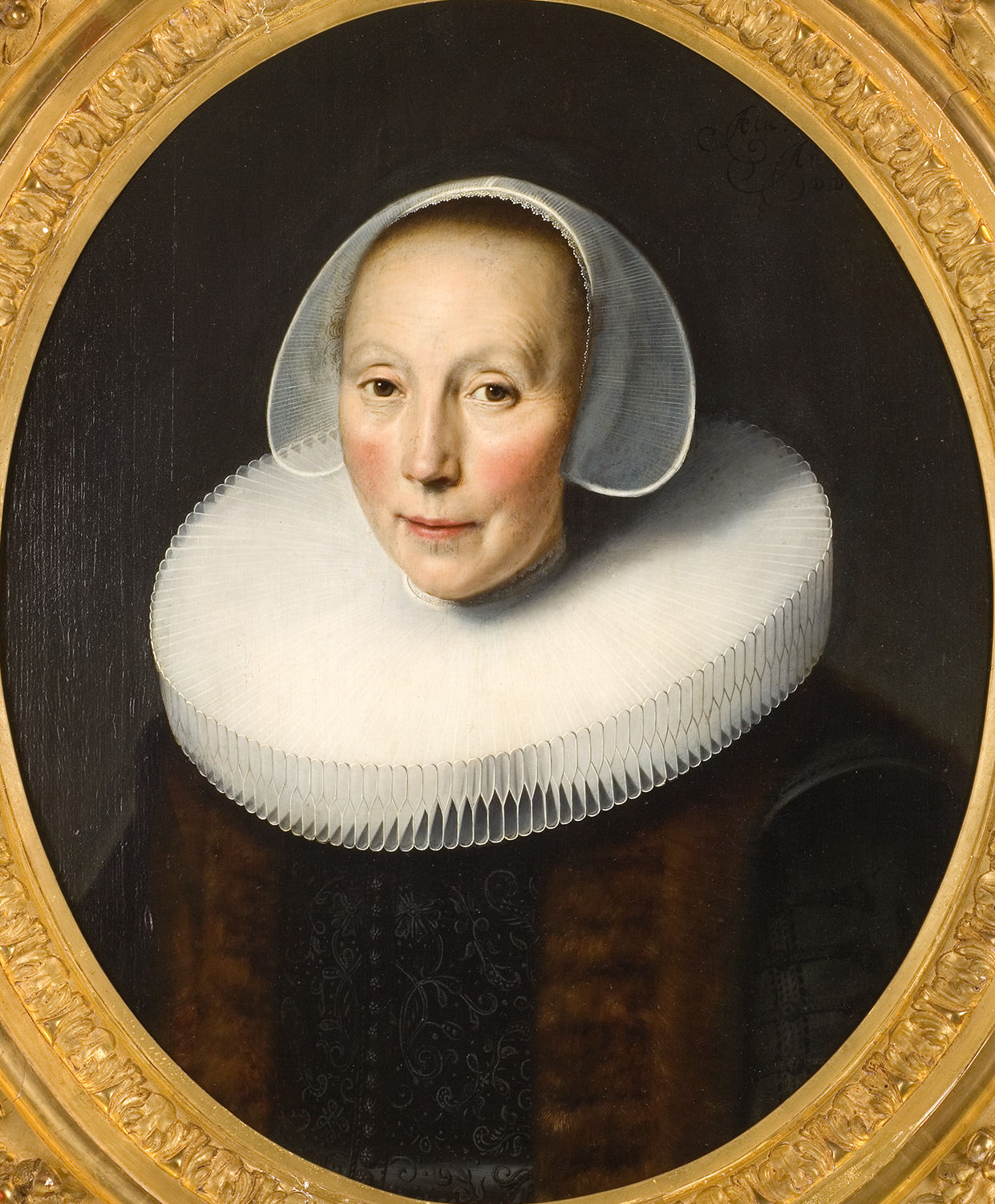 L'image présente un portrait d'une femme au visage serein, coiffée d'un grand col en dentelle blanche. Elle porte une robe sombre, et son teint clair est mis en valeur par le contraste. Son expression est douce et elle regarde droit vers le spectateur. Le cadre doré souligne l'élégance de l'œuvre. Ce style de portrait est typique des peintures du XVIIe siècle.