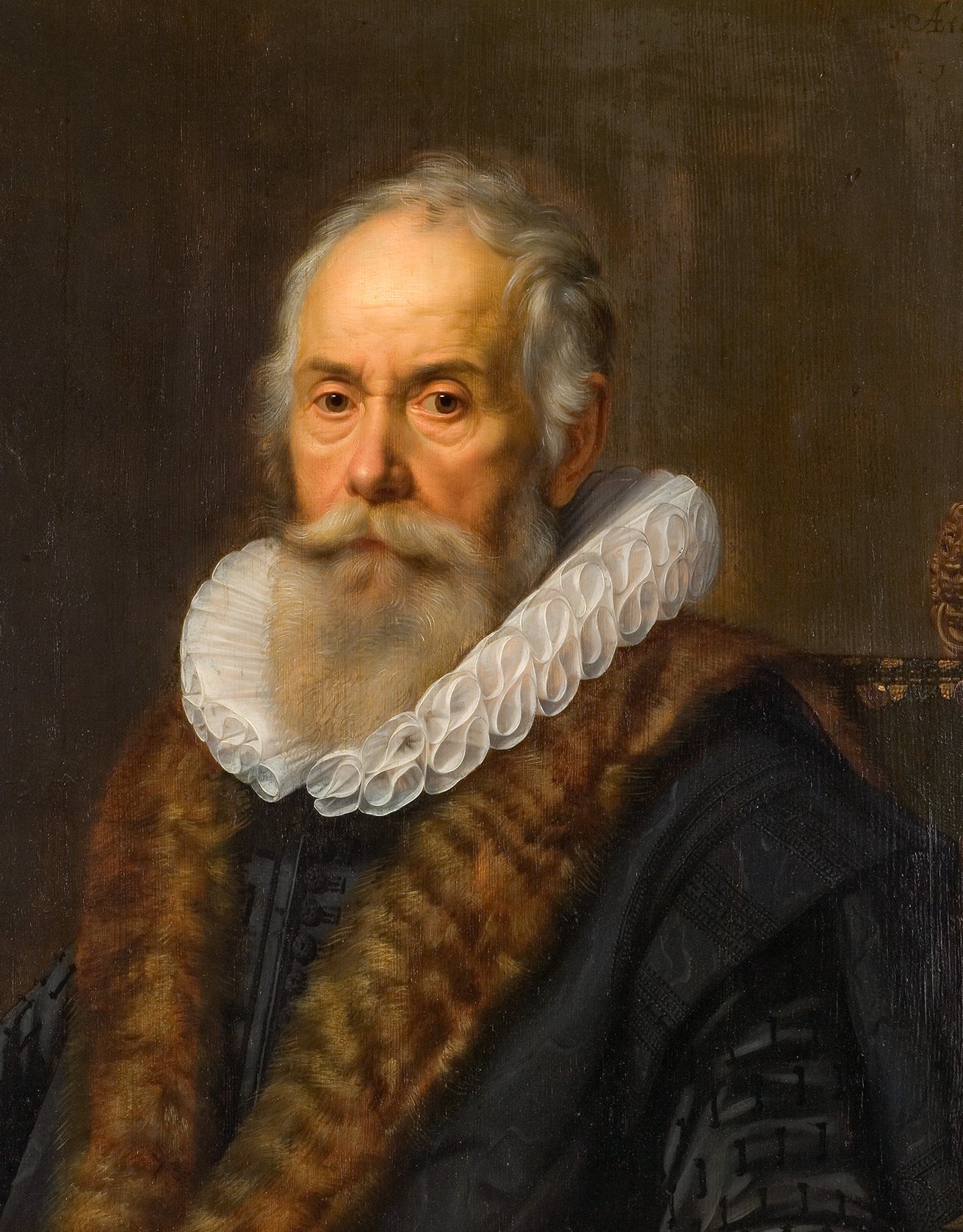 L'image est un portrait d'un homme âgé, présentant un visage marqué par le temps avec une longue barbe et des cheveux gris. Il porte un col en dentelle blanche, ainsi qu'un manteau orné de fourrure, ce qui indique un statut social élevé. Le fond du tableau est sombre, mettant en valeur les détails de son expression et de ses vêtements. L'artiste a réussi à capturer une certaine sagesse et autorité dans le regard du personnage.