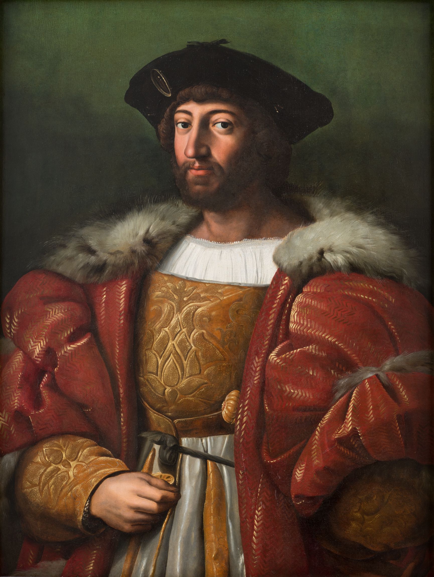 L'image représente un homme en tenue de cour, portant un large manteau rouge orné de fourrure. Il porte aussi un chapeau noir et arbore un regard confiant. Son vêtement sous le manteau est richement décoré, avec des motifs dorés. L'arrière-plan est d'une teinte verte uniforme, focalisant l'attention sur sa figure.