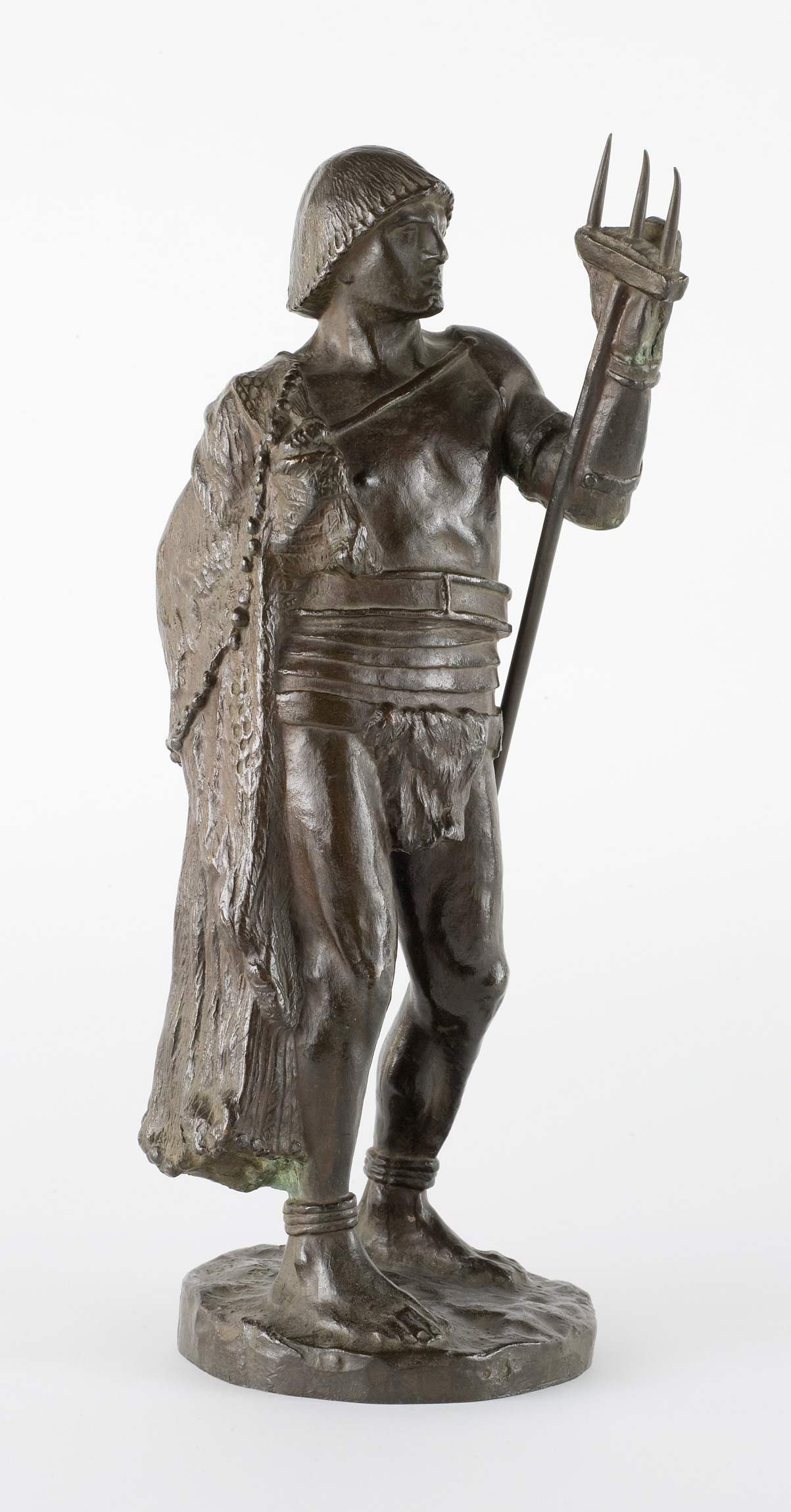 Cette image représente une sculpture en bronze d'un homme debout, vêtu d'un costume antique. Il porte un pagne et un manteau drapé sur une épaule, avec des détails texturés qui ajoutent à son apparence. Dans une main, il tient un trident, ce qui suggère qu'il pourrait être un personnage lié à la mer ou à la mythologie. Son expression est sérieuse et déterminée, et il semble regarder vers l'avant, ce qui donne une impression de force et de dignité. La base de la sculpture est détaillée et complète l'œuvre avec une finition raffinée.