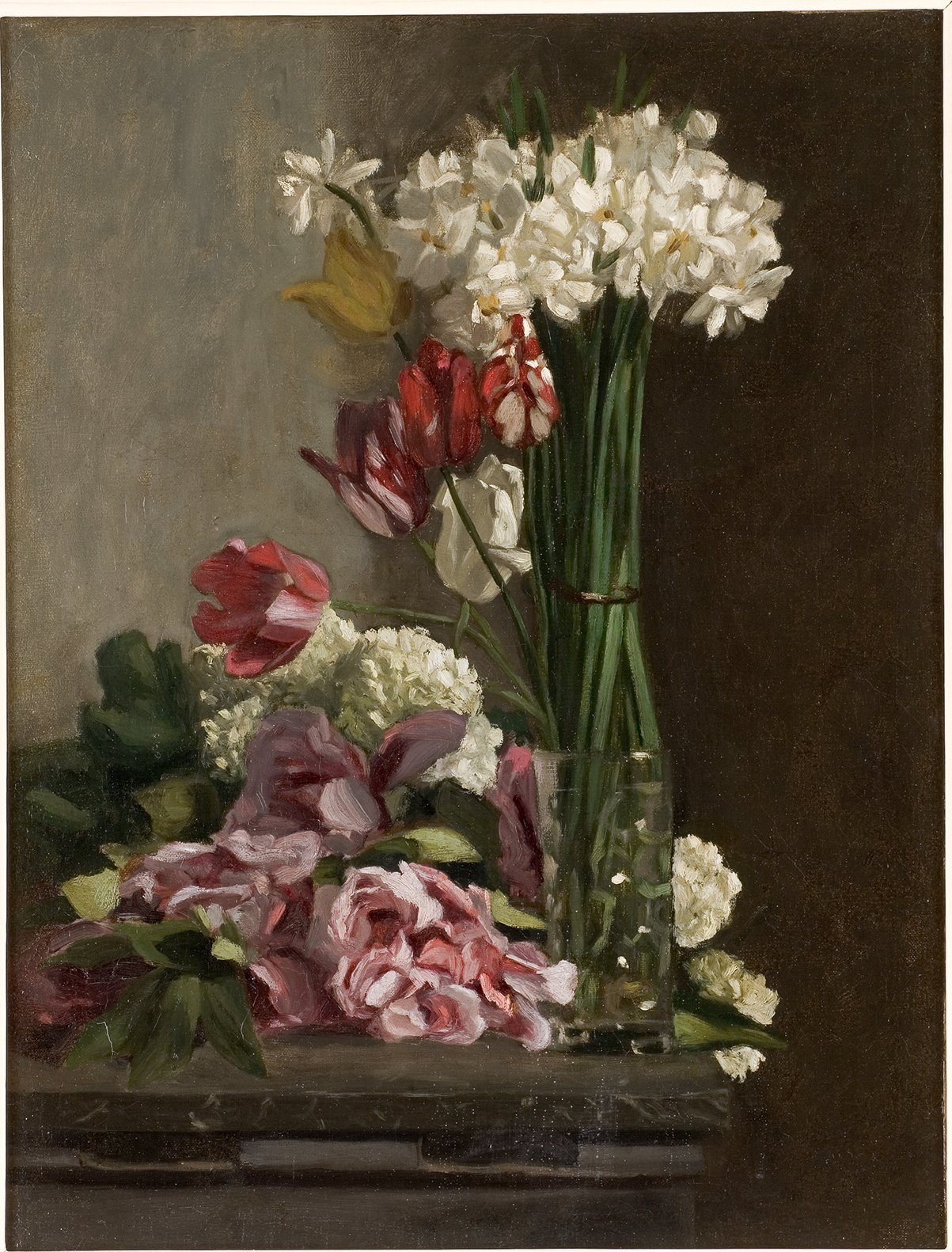 Cette image représente un joli bouquet de fleurs disposé dans un vase. On peut y voir des tulipes rouges, des narcisses blancs, ainsi que des pivoines roses et d'autres fleurs. Le bouquet est agrémenté de verdure et se trouve sur une surface sombre, mettant en valeur les couleurs vives des fleurs. L'ensemble dégage une atmosphère paisible et naturelle.