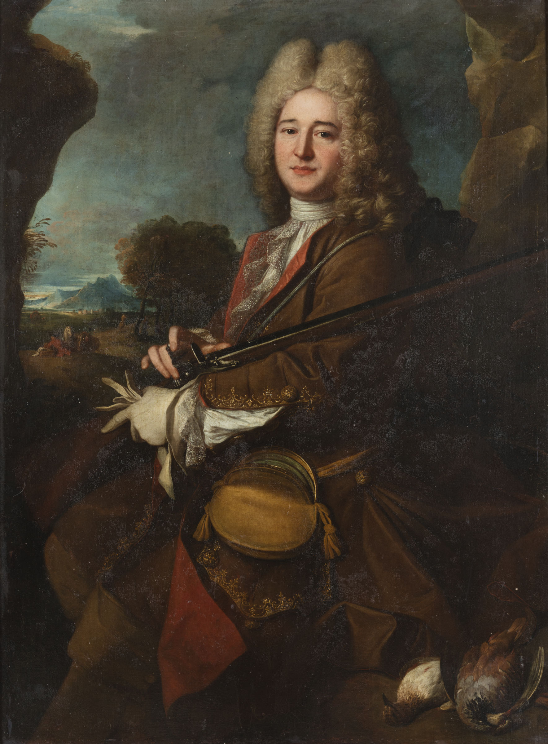 L'image représente un portrait d'un homme aristocratique du XVIIIe siècle, vêtu d'un habit richement orné. Il a des cheveux longs et bouclés. L'homme est assis dans un paysage naturel, tenant une arme à feu (comme une carabine ou un fusil) et semblant contempler la scène autour de lui. En arrière-plan, on peut apercevoir des arbres et des collines, ainsi qu'une vue sur une étendue d'eau. Le tableau dégage une atmosphère de noblesse et de sérénité, typique des portraits de l'époque baroque.