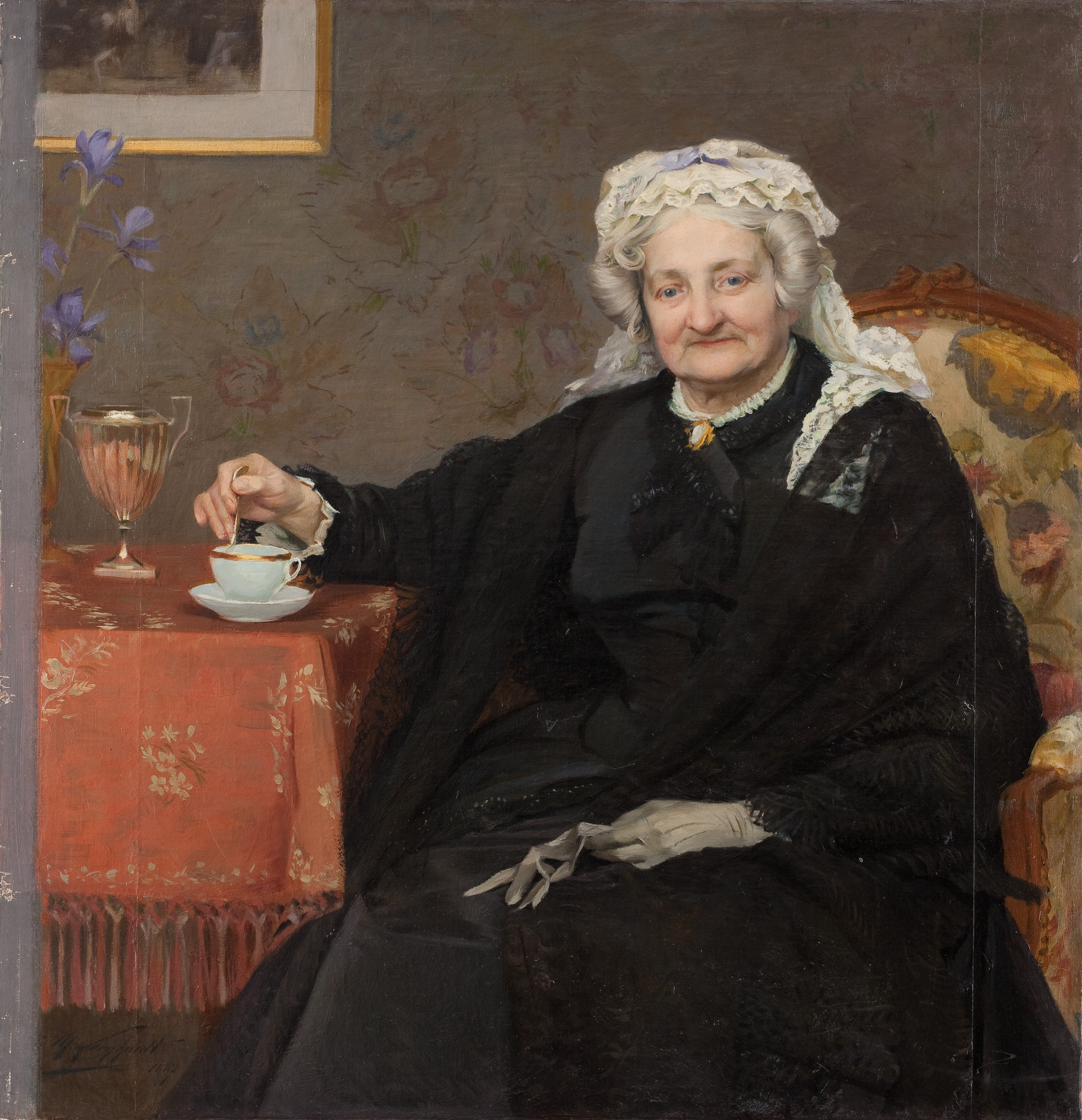 L'image montre une femme âgée assise dans un fauteuil. Elle porte une robe noire avec un châle et un bonnet, affichant une expression douce et sereine. Sur la table à côté d'elle, il y a une petite tasse de thé et un verre décoratif. En arrière-plan, des éléments de décoration tels qu'un tableau et des fleurs ajoutent une touche d'élégance à la scène. L'atmosphère est chaleureuse et nostalgique.