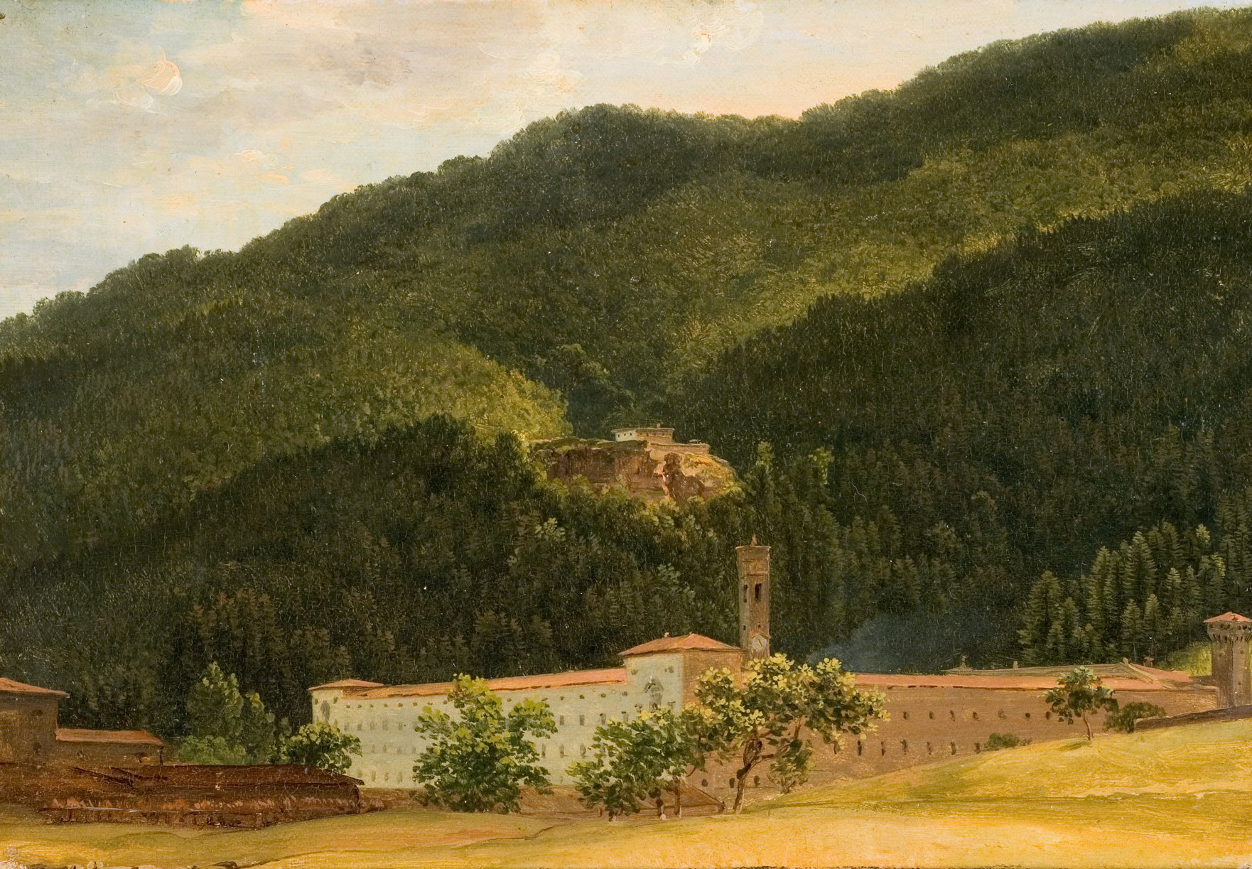 L'image présente un paysage rural avec des collines verdoyantes. Au premier plan, on peut voir un bâtiment assez large, probablement une ancienne abbaye ou un monastère, entouré d'un terrain dégagé. À l'arrière-plan, les collines sont recouvertes de forêts denses, créant un contraste agréable avec le paysage. Une structure en hauteur, peut-être une ruine ou un petit édifice, est visible sur la colline. L'ensemble de la scène évoque une atmosphère tranquille et paisible.