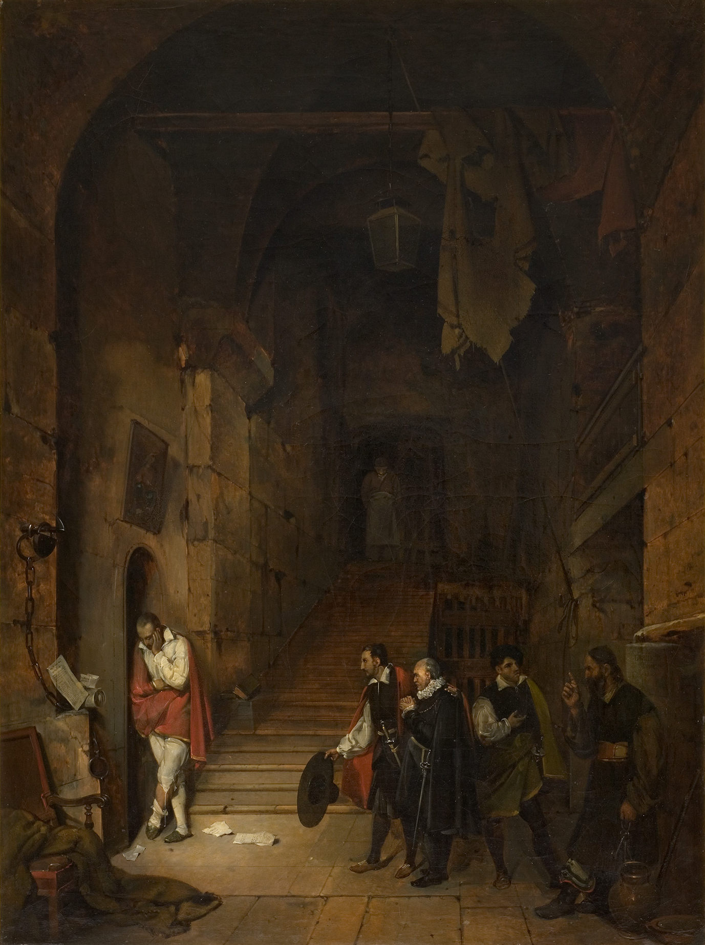 L'image représente une scène dramatique se déroulant dans un intérieur sombre, probablement une prison ou un château. Au premier plan, un homme en costume, tenant une épée, est à la porte d'une cellule, semblant hésiter ou en proie à l'incertitude. Derrière lui, un groupe de figures s'avance, dont un homme portant un bouclier et d'autres vêtus de vêtements d'époque. L'atmosphère est tendue, accentuée par l'éclairage et les ombres qui mettent en valeur les détails architecturaux. Au fond, un escalier en colimaçon mène à un étage supérieur, ajoutant à la profondeur de la scène. L'ensemble donne une impression de mystère et de suspense.