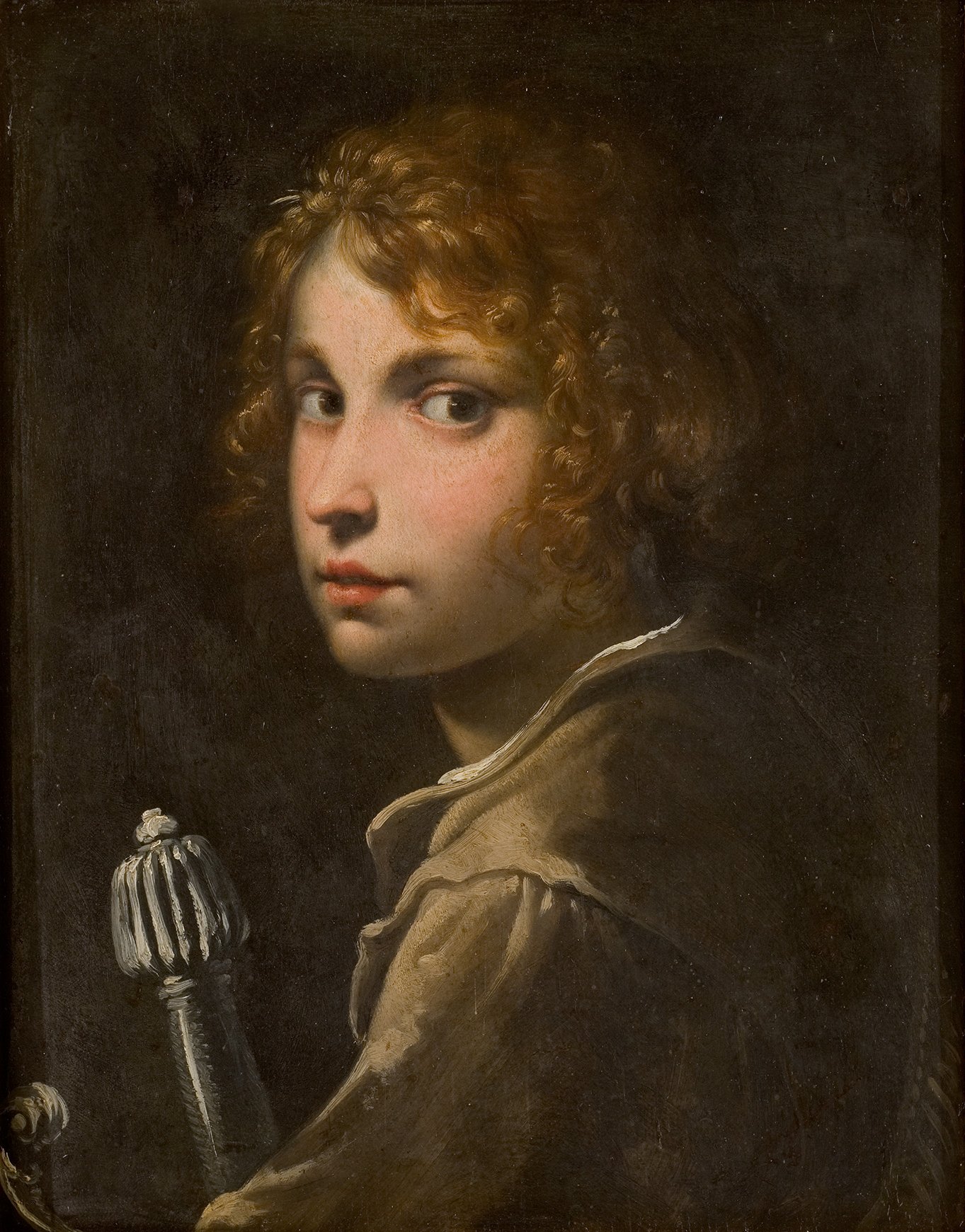 Cette image représente un portrait d'un jeune homme au visage délicat, avec des cheveux bouclés et un air pensif. Il se tourne légèrement sur le côté, regardant au-dessus de son épaule. La lumière met en valeur ses traits, en contrastant avec un fond sombre qui accentue son expression. Il tient un objet, peut-être un sceptre ou un bâton, ce qui lui confère une certaine gravité. Les couleurs sont subtiles, et l'utilisation de la lumière et de l'ombre crée une atmosphère à la fois mystérieuse et intime.