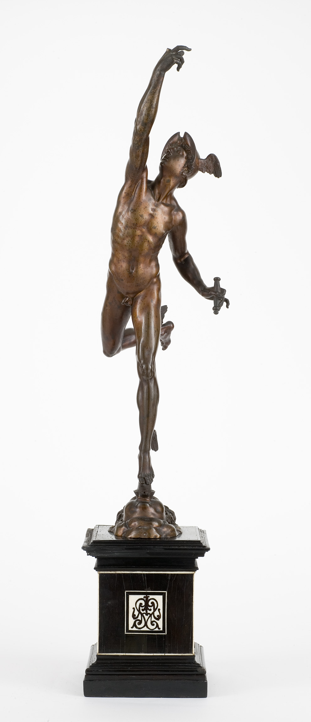 Cette image représente une sculpture en bronze d'un homme nu, en mouvement dynamique. Il se tient sur une jambe, l'autre jambe replie derrière lui, et l'une de ses bras est levé, tenant un objet qui semble être une sorte de lance ou de glaive. La sculpture est posée sur un socle élégant, soulignant le détail et le mouvement du bronze. Les proportions du corps sont harmonieuses, évoquant une impression de légèreté et de grâce. L'ensemble donne une sensation de vitalité et de puissance.