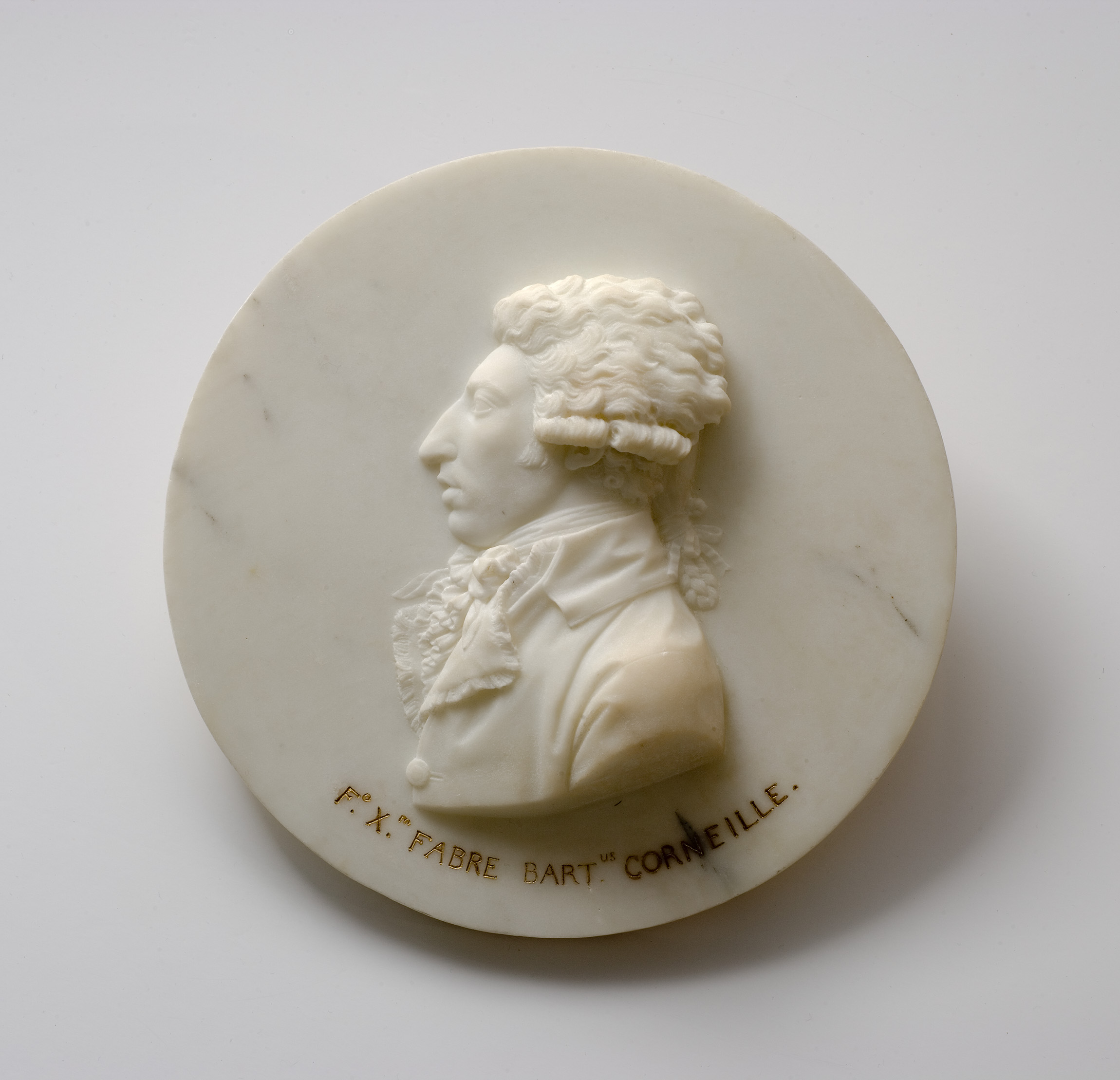 Cette image représente un médaillon en marbre, sur lequel est sculpté un portrait en relief d'un homme, vu de profil. L'œuvre est finement détaillée, mettant en évidence les traits du visage et la coiffure de la personne. En dessous du portrait, on peut voir une inscription qui mentionne "F.X. Fabre Bart" et "Corneille". Le fond du médaillon est lisse et de couleur claire, ce qui accentue le contraste avec le relief du visage.
