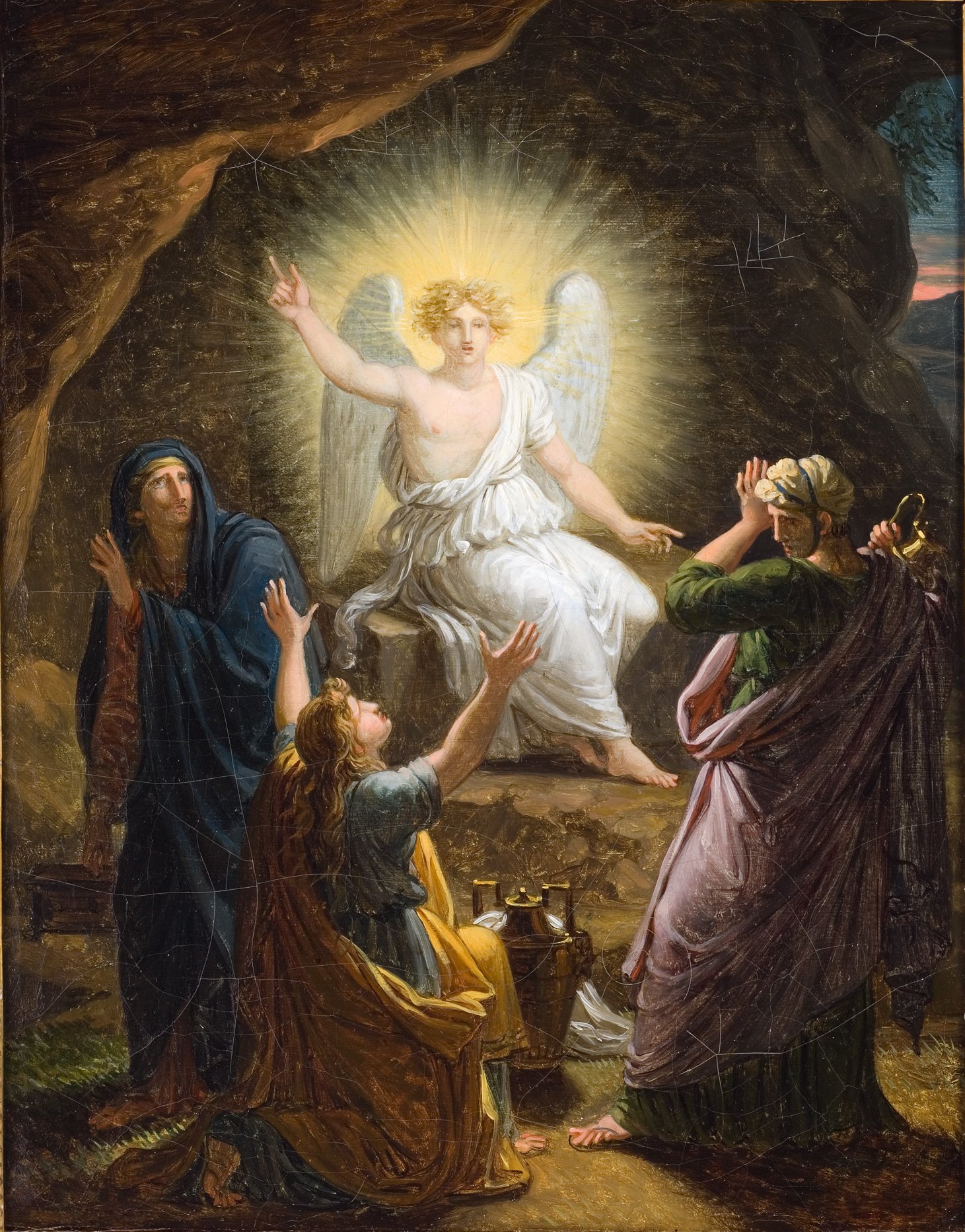 L'image représente un moment biblique, probablement la résurrection de Jésus. On y voit un ange radiant aux ailes blanches, assis sur une pierre à l'entrée d'une grotte. L'ange est entouré de lumière, symbolisant la divinité et la pureté. Devant lui, plusieurs femmes se tiennent, les bras levés en signe d'étonnement ou de dévotion. Elles semblent porter des vêtements traditionnels de l'époque, et leur expression reflète la surprise et la vénération. Les couleurs de la scène sont chaleureuses, créant une atmosphère à la fois mystique et apaisante.