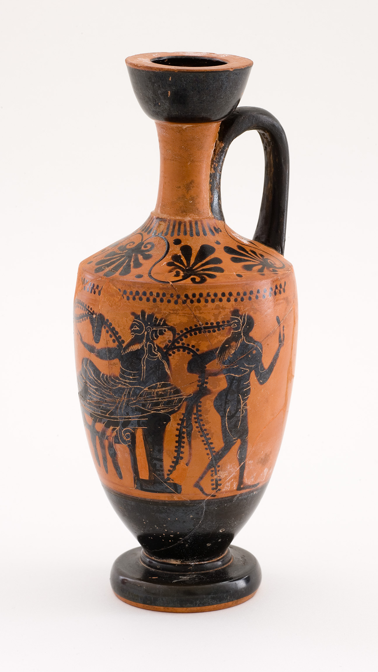 Cette image représente une amphore en terre cuite de style grec ancien. L'objet présente une forme élancée avec un long cou et une anse. La surface est décorée de motifs géométriques et de scènes narratives, illustrant des personnages en mouvement. Les figures sont représentées avec des détails précis, souvent en noir sur un fond ocre, typique de la céramique à figures noires de cette époque. La vase semble avoir été utilisé pour contenir des liquides, comme de l'huile ou du vin.