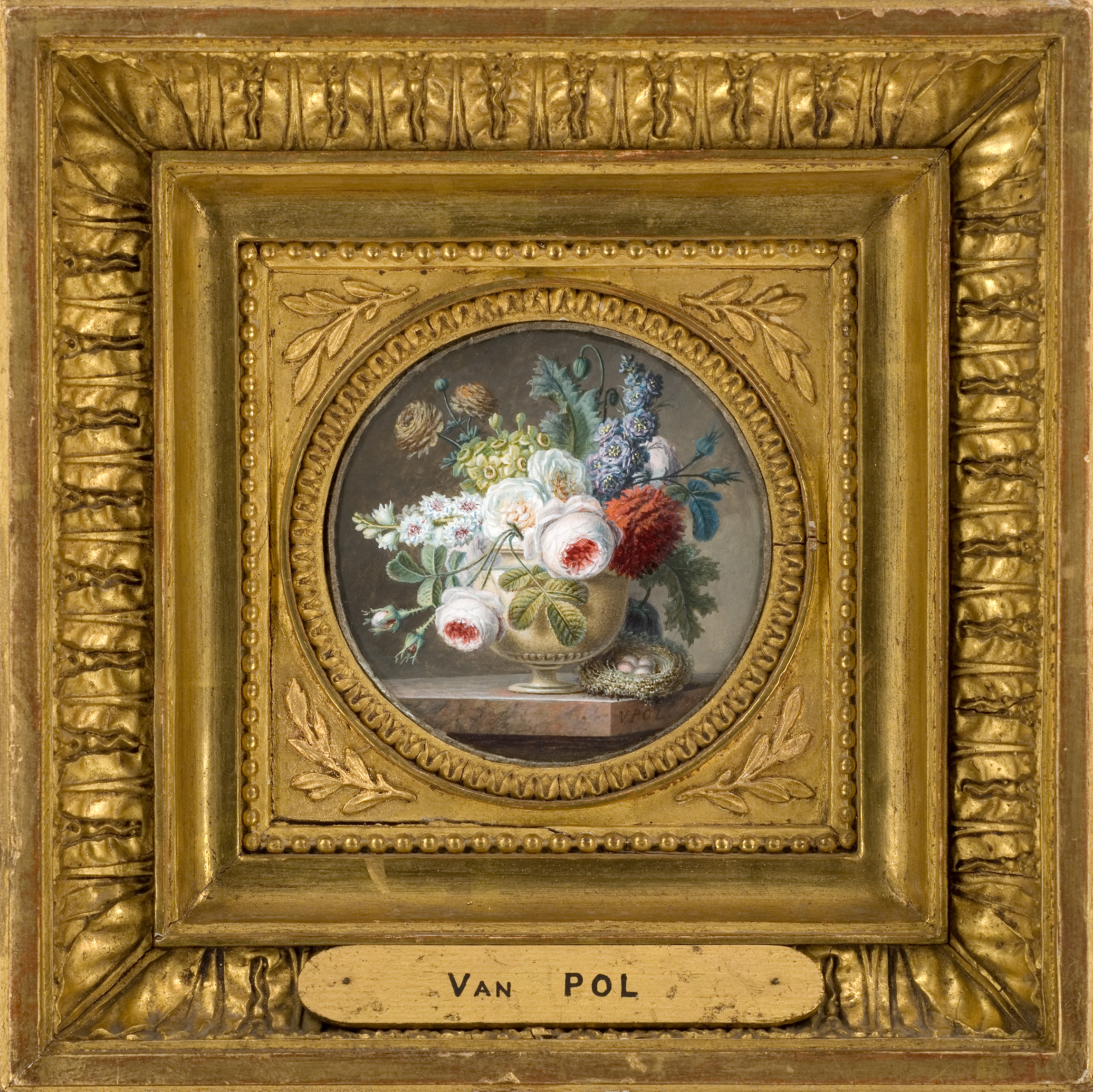 L'image montre une délicate peinture représentant un vase rempli de fleurs. Le vase est orné de divers types de fleurs aux couleurs vives, incluant des fleurs blanches, rouges et bleues. L'ensemble est présenté dans un cadre doré et richement décoré, ajoutant une touche d'élégance. Le nom "Van Pol" est visible sur une plaque en bas du cadre, indiquant possiblement l'artiste ou le collectionneur. L'ambiance générale est artistique et raffinée.