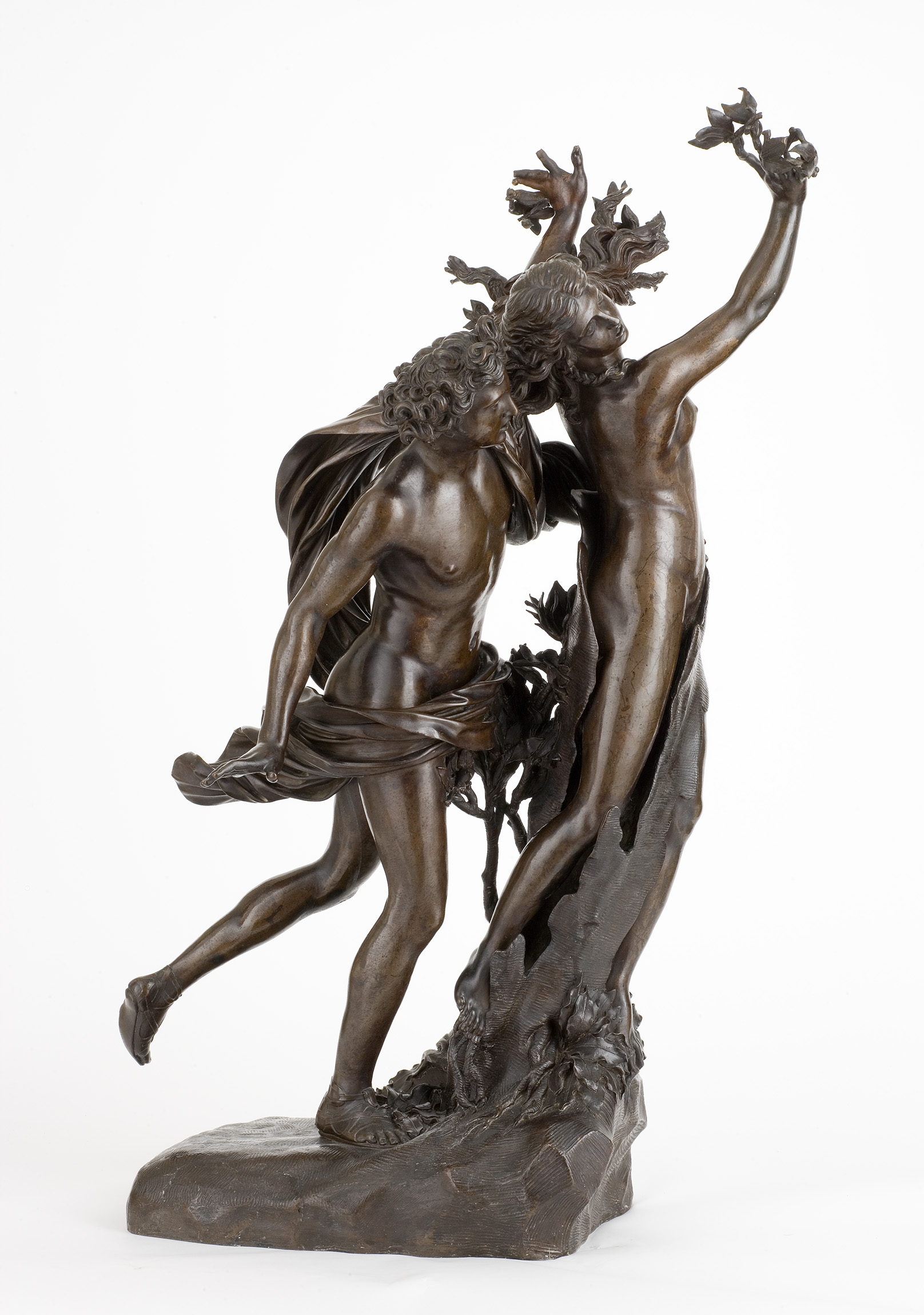 Cette image représente une sculpture en bronze d'un couple dynamique. L'un des personnages, masculin, est en mouvement, ses bras tendus vers l'avant, tandis que l'autre, féminin, semble se tourner vers lui, avec des éléments naturels, comme des feuilles ou des branches, intégrés à sa coiffure. Les détails du travail du métal montrent un souci du réalisme et de l'élégance, évoquant une connexion entre la nature et l'humanité. La pose des personnages transmet une certaine passion et une interaction fluide entre eux.