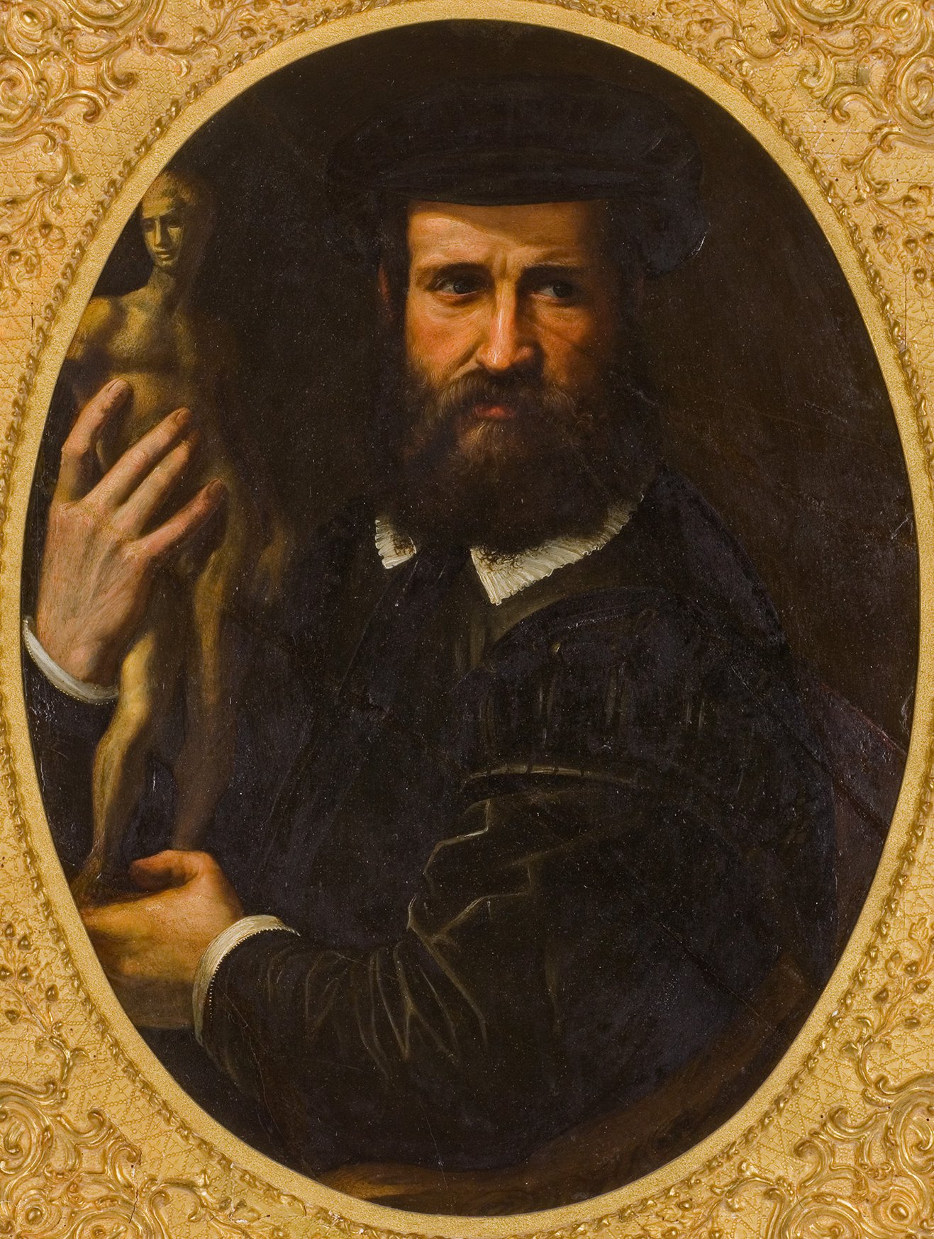 Cette image représente un homme au regard intense, portant une barbe et un chapeau noir. Il est vêtu de vêtements sombres avec un col en dentelle. Dans sa main droite, il tient une petite statue ou un modèle sculptural, et son expression semble à la fois réfléchie et confiante. Le fond est sombre, ce qui met en valeur son visage et la sculpture. Le cadre est doré et orné, ajoutant une touche de sophistication à l'ensemble.