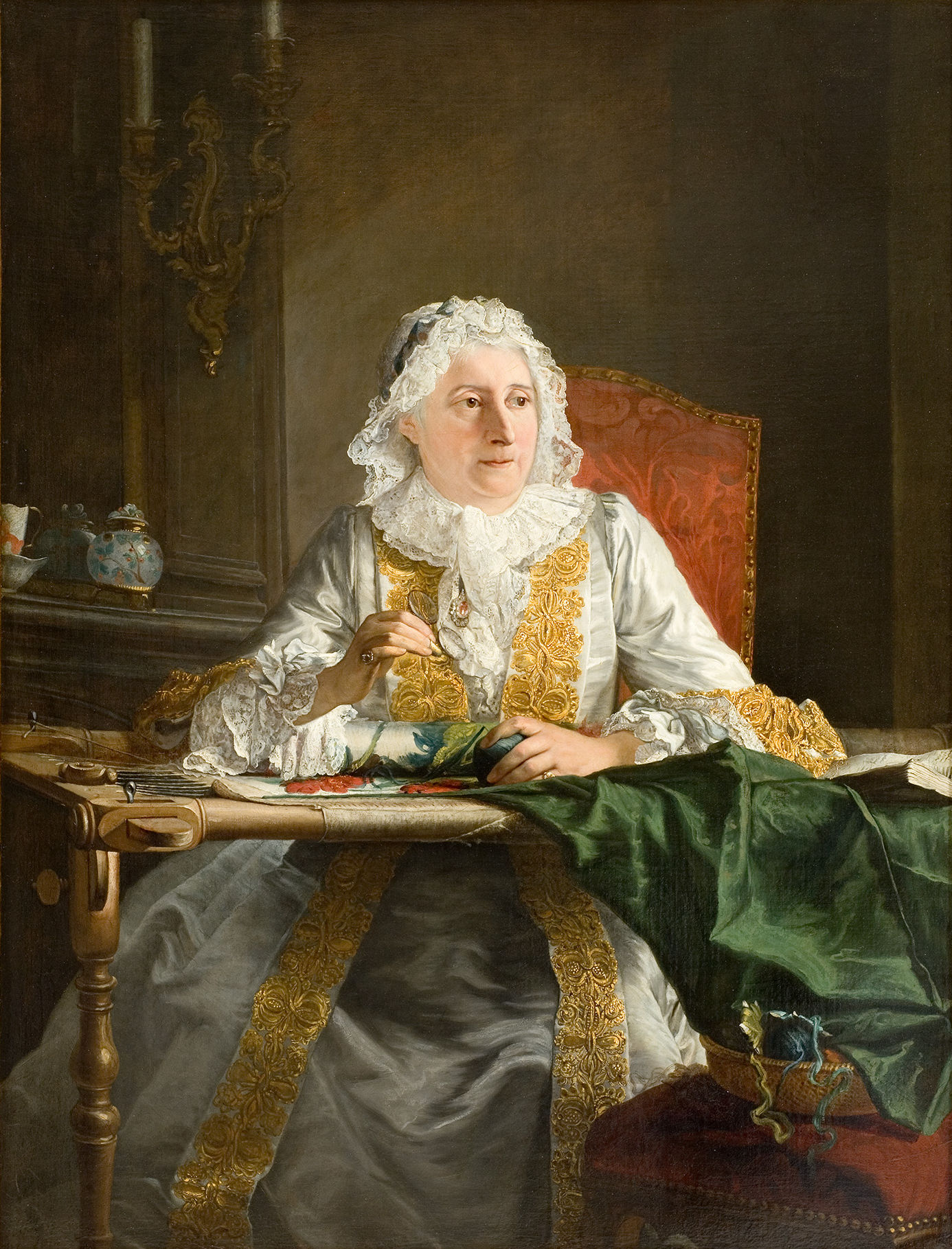 Cette image représente une femme assise à une table, occupée à broder. Elle porte une robe élégante, ornée de riches détails dorés, ainsi qu'un bonnet blanc en dentelle. Son expression est concentrée et sérieuse alors qu'elle tient une aiguille et travaille sur un morceau de tissu vert. L'arrière-plan est sombre, mettant en valeur la lumière sur elle et son environnement. On peut apercevoir des objets décoratifs sur la table et un lustre murale, ce qui évoque un cadre bourgeois et raffiné.