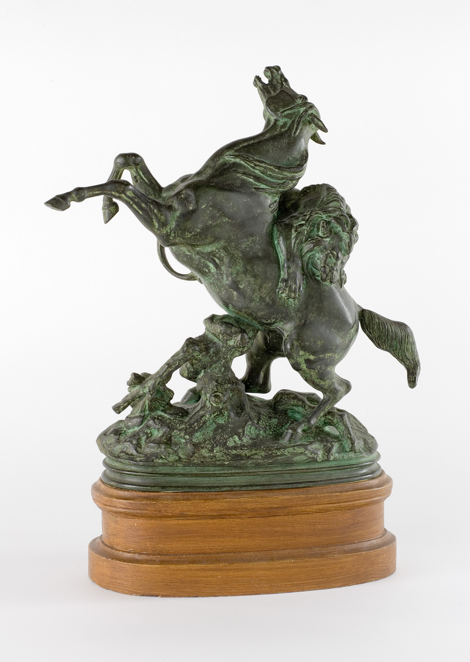 L'image montre une sculpture en bronze représentant un cheval en position de bataille, cabré sur ses pattes arrière. La scène est dynamique, avec des détails finement travaillés : les muscles du cheval et l'expression de sa tête sont particulièrement expressifs. Le cheval se tient sur un socle en bois, qui ajoute une touche élégante à l'ensemble. Cette œuvre évoque à la fois la force et la grâce de cet animal.