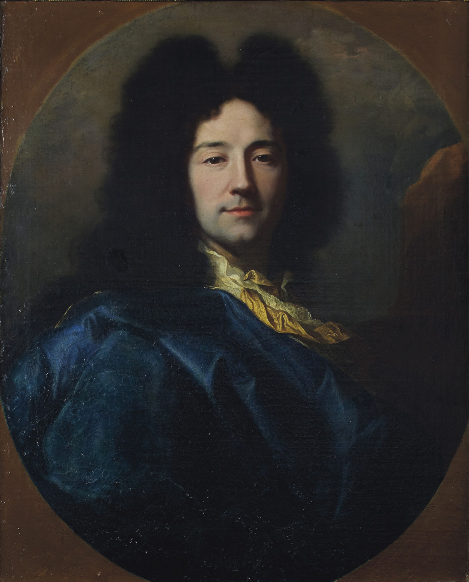 L'image représente un portrait d'un homme, dont le visage est tourné vers la droite. Il a de longs cheveux bouclés, de couleur sombre, et porte une tenue élégante avec une large col ornée. Le fond est sombre, mettant en valeur les couleurs profondes de son vêtement, qui est d'un bleu riche. L'éclairage doux crée une ambiance chaleureuse et accentue ses traits.