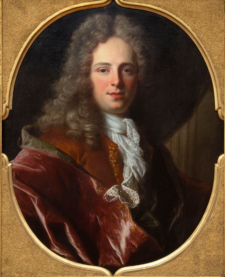 L'image montre un portrait d'un homme au visage doux et expressif. Il a des cheveux longs et bouclés, d'un ton clair, et porte un habit richement orné de velours rouge et de broderies dorées. Sa chemise est blanche avec un jabot en dentelle, ce qui ajoute à son élégance. L'arrière-plan de l'image est sobre, ce qui met en valeur la personnalité du sujet. Le cadre est en or, ce qui accentue le caractère prestigieux de la peinture.