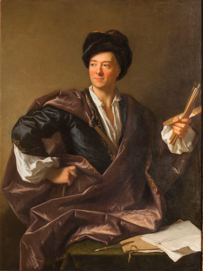 L'image représente un homme d'origine européenne, vêtu d'un costume élégant avec des couleurs riches, notamment du noir et du violet. Il porte un chapeau à la mode, et son expression est détendue et confiante. Dans sa main, il tient plusieurs outils de dessin ou des pinceaux, tandis qu'il repose sur une table sur laquelle sont posés des papiers et un crayon. L'arrière-plan est neutre, mettant en valeur le sujet au centre de la composition.