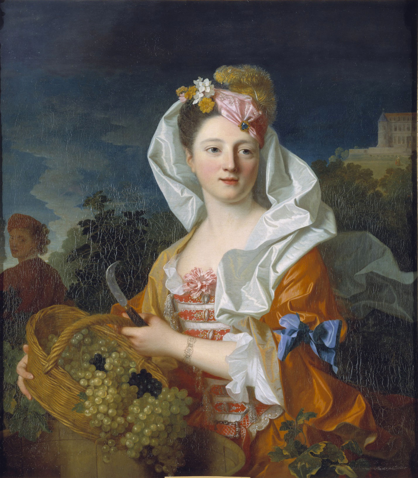 L'image représente une femme vêtue d'une élégante robe colorée, ornée de détails raffinés. Elle se tient devant un paysage avec un panier rempli de raisins devant elle. Sa coiffure est richement embellie avec des fleurs et un grand noeud. L'arrière-plan montre des collines et un bâtiment, ajoutant une touche de nature et de sérénité à la scène. L'expression de la femme est douce et invitante, évoquant une atmosphère de fraîcheur et de joie.