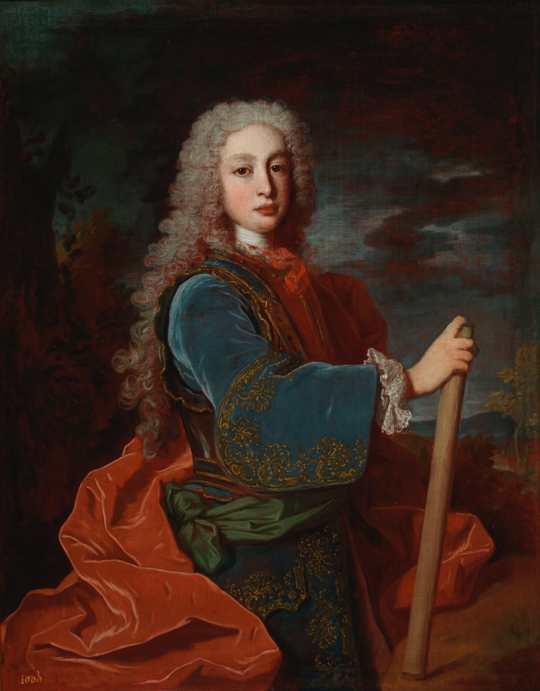 L'image représente un portrait d'un jeune homme en tenue historique. Il porte un vêtement richement orné de couleur bleue, avec des motifs dorés, et une cape rouge éclatante drapée sur son épaule. Le jeune homme a de longs cheveux bouclés et affiche une expression confiante, tenant un bâton dans une main. L'arrière-plan est sombre, ce qui met en valeur sa figure et les détails de sa tenue.