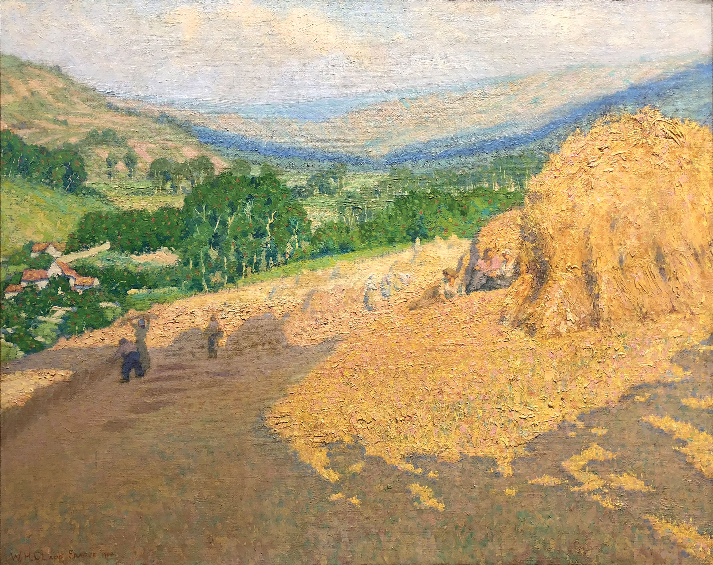 L'image représente un paysage rural, probablement à la fin de l'été ou au début de l'automne. Au premier plan, on remarque des meules de foin bien formées sur un sol jaune. À l'arrière-plan, des collines verdoyantes s'élèvent, avec des arbres dispersés qui ajoutent de la vie à la scène. Le ciel est partiellement nuageux, suggérant une luminosité douce. Quelques figures humaines, à peine visibles, semblent être en train de travailler dans les champs. L'ensemble dégage une atmosphère sereine et bucolique, typique de la vie à la campagne.