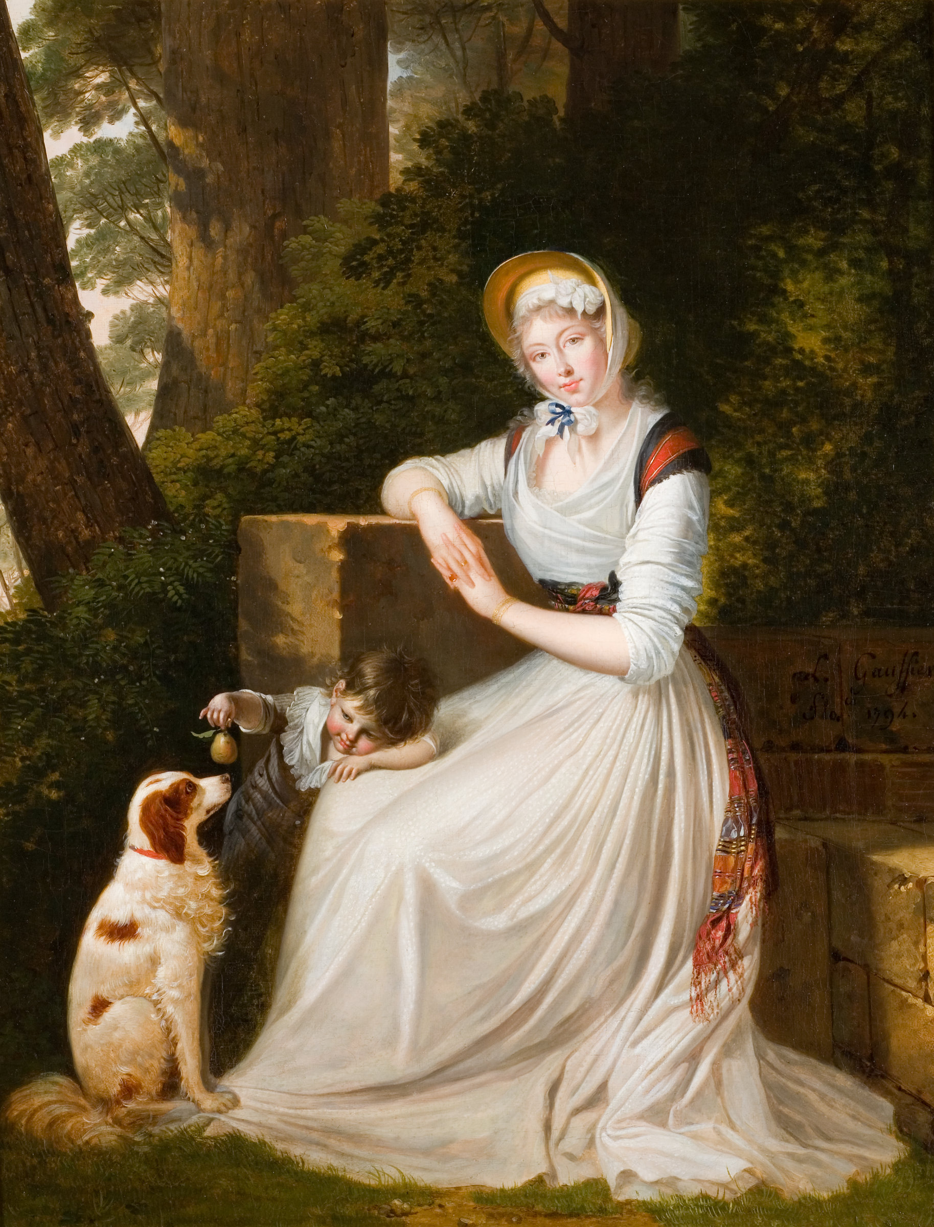 L'image représente une scène paisible où une femme en robe blanche assise près d'une pierre semble contemplative. Elle porte un bonnet et des accessoires traditionnels, et un enfant à sa droite s'amuse avec un petit objet. Un chien parmi eux ajoute une touche de douceur à la scène. Le fond est composé de verdure, créant une atmosphère tranquille et bucolique.