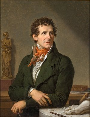 L'image représente un portrait de profil d'un homme élégant, avec des cheveux bruns et frisés. Il porte un habit en tissu sombre, orné d'un col et d'une cravate colorée. Son expression est réfléchie et engageante. À l'arrière-plan, on peut voir une statue de femme, ainsi que des outils d'artisanat sur une table. L'ambiance générale dégage une impression de sophistication et d'intellectualisme, suggérant peut-être que l'homme est un artiste ou un intellectuel.