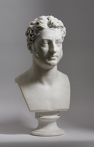 L'image montre un buste en marbre représentant un homme. Ce buste présente des traits sculptés avec soin, notamment des cheveux bouclés et une expression faciale calme. Le buste repose sur un socle rond élégant, et l'ensemble dégage une impression de dignité et de sophistication. Le marbre est polie, ce qui lui confère un aspect lumineux et raffiné. La composition est simple et met en valeur le savoir-faire artistique de la sculpture.