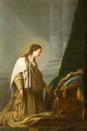 L'image montre une femme en prière, vêtue d'une robe claire avec un drapé sur les épaules. Elle est agenouillée, les mains légèrement levées, dans une posture de dévotion. Son expression est sereine et contemplative. À côté d'elle, un meuble ou un autel est visible, recouvert de tissus riches, suggérant une atmosphère sacrée. L'éclairage met en valeur les détails de sa figure et de son environnement, créant une ambiance paisible et spirituelle.